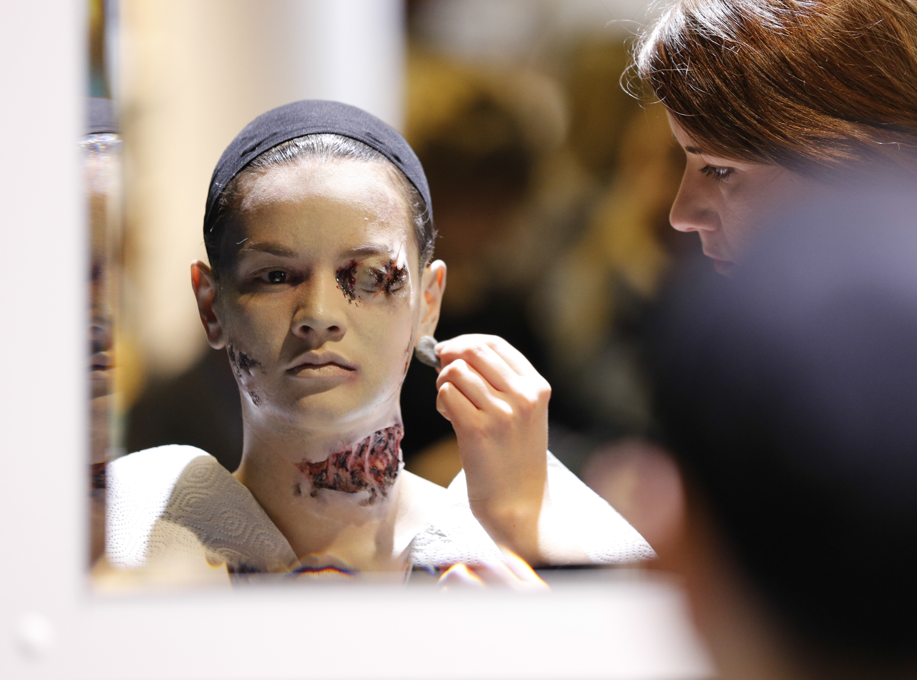 Make-up Artist Aisha King applying make-up and prosthetics for a floater SFX make-up during the Championship for Make-up Artists in Training.